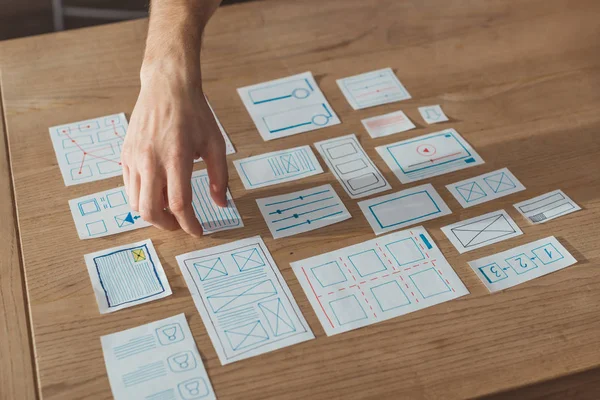 Vista recortada del diseño de la experiencia del usuario de planificación de diseño con bocetos en la mesa - foto de stock