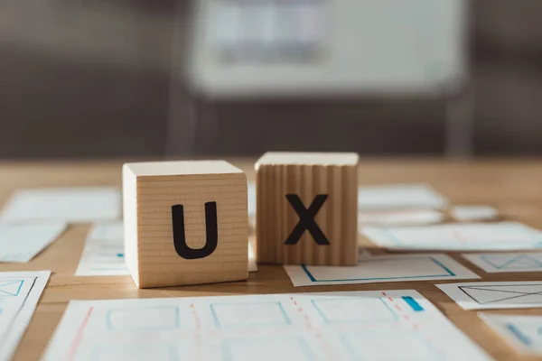 Concentration sélective de cubes avec des lettres ux et des esquisses d'applications de concepteur sur la table — Photo de stock