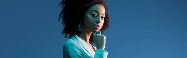 Панорамний знімок привабливої афроамериканської жінки в костюмі ізольовано на синьому — стокове фото