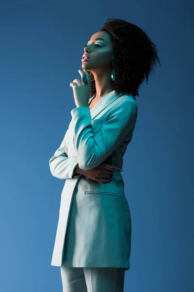 Atractiva mujer afroamericana en traje aislado en azul — Stock Photo