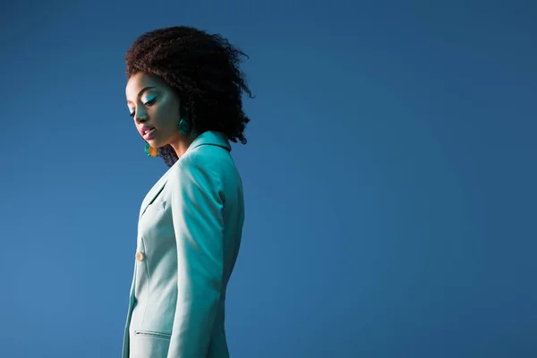 Atractiva mujer afroamericana en traje aislado en azul - foto de stock