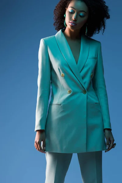 Atractiva mujer afroamericana en traje aislado en azul - foto de stock