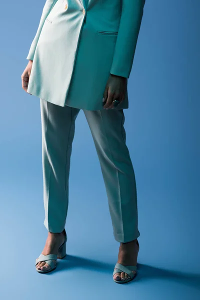 Cropped view of african american woman in suit on blue background — Stock Photo