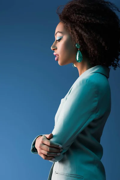 Вид збоку приваблива афроамериканська жінка в костюмі ізольована на синьому — стокове фото