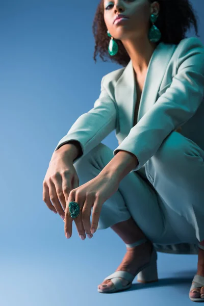 Cropped view of african american woman in elegant suit on blue background — Stock Photo