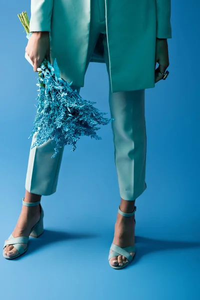 Vista recortada de mujer afroamericana sosteniendo ramo sobre fondo azul - foto de stock