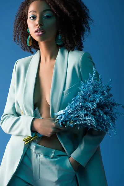 Atractiva mujer afroamericana sosteniendo ramo aislado en azul - foto de stock