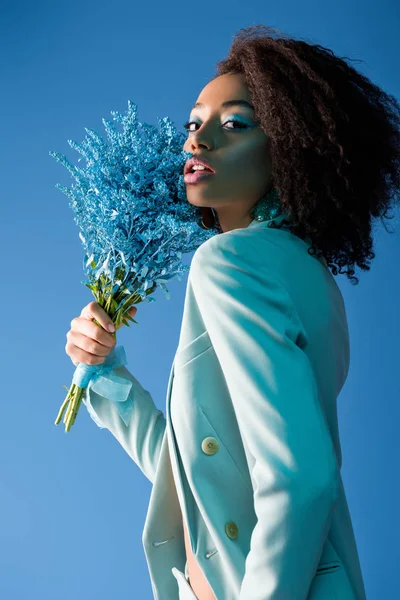 Attraente donna afro-americana tenendo bouquet isolato su blu — Foto stock