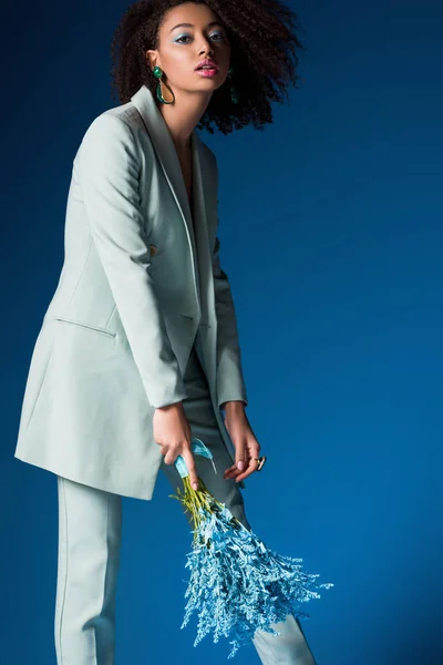 Attraktive afrikanisch-amerikanische Frau hält Blumenstrauß isoliert auf blau — Stockfoto