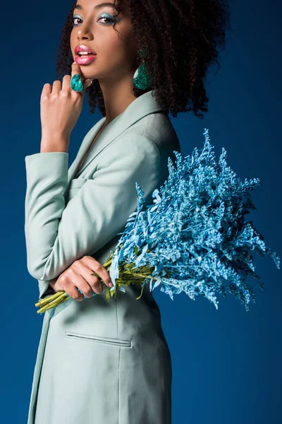 Attrayant afro-américaine femme tenant bouquet isolé sur bleu — Photo de stock