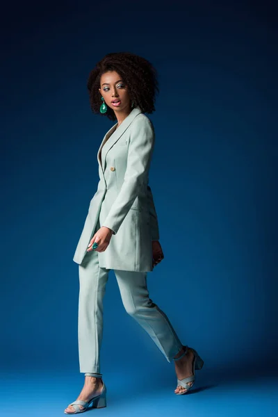 Attraente donna afro-americana che cammina su sfondo blu — Foto stock