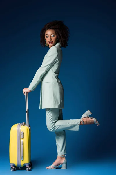 Sorridente afro-americano mulher segurando saco de viagem no fundo azul — Fotografia de Stock