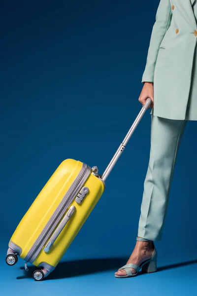 Cropped view of african american woman holding travel bag on blue background — Stock Photo