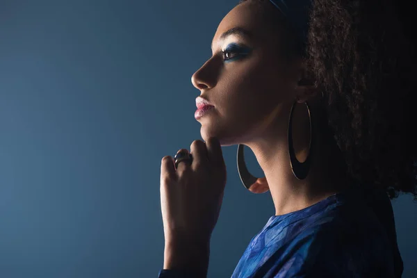 Side view of attractive african american woman with accessories isolated on blue — Stock Photo