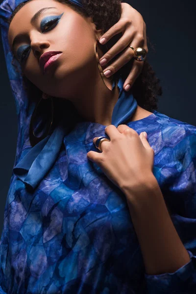 Stylische afrikanisch-amerikanische Frau mit Ohrringen schaut in die Kamera isoliert auf schwarz — Stockfoto