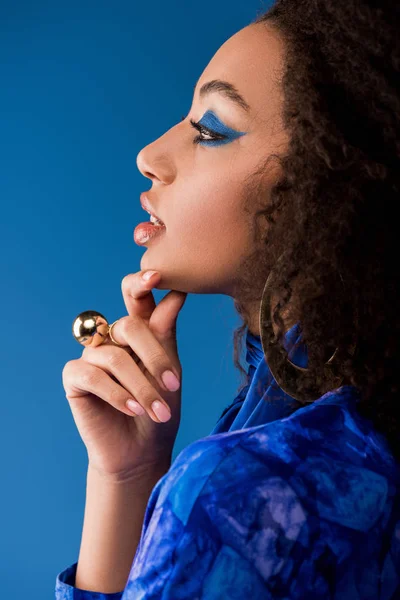 Vista lateral da mulher americana africana com maquiagem isolada em azul — Fotografia de Stock