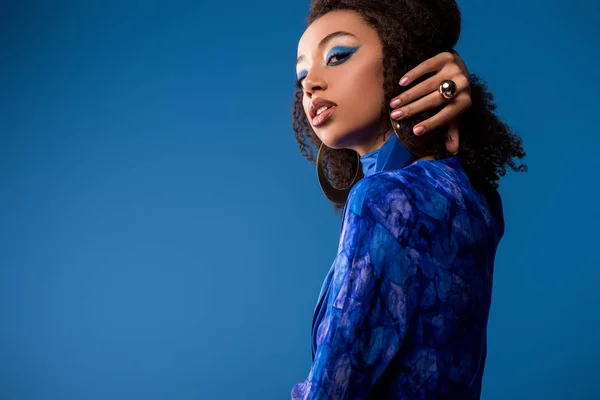 Attractive african american woman in stylish dress looking at camera isolated on blue — Stock Photo