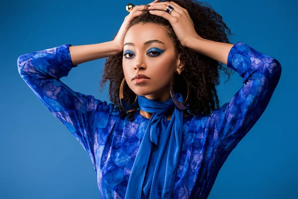 Stylish african american woman in dress looking at camera isolated on blue — Stock Photo