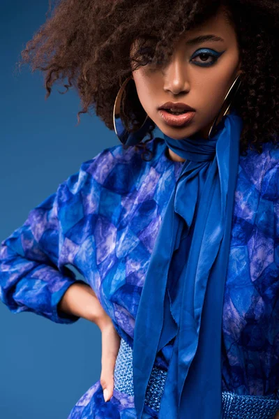 Stylish african american woman in dress looking at camera isolated on blue — Stock Photo