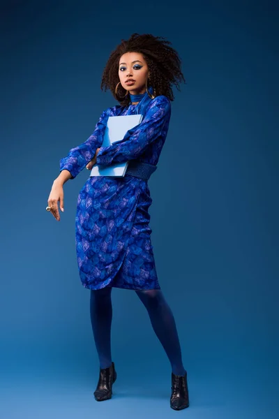 Attrayant afro-américaine femme tenant dossier sur fond bleu — Photo de stock