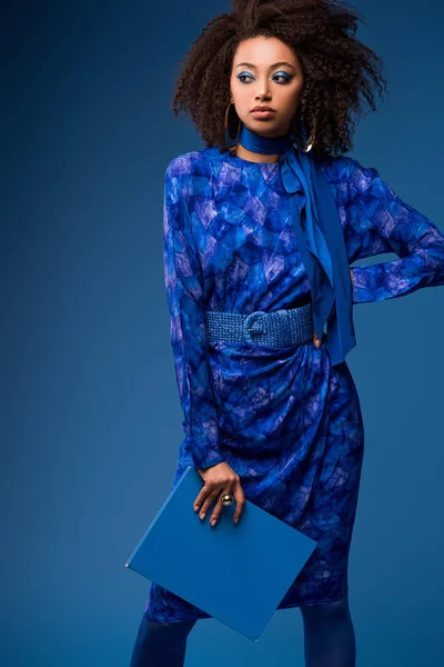 Atractivo africano americano mujer celebración carpeta aislado en azul - foto de stock