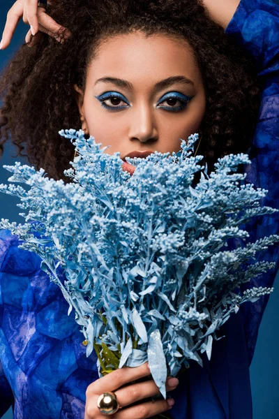 African american woman with makeup holding bouquet isolated on blue — Stock Photo