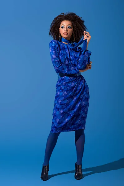 Atractiva mujer afroamericana en vestido sobre fondo azul - foto de stock