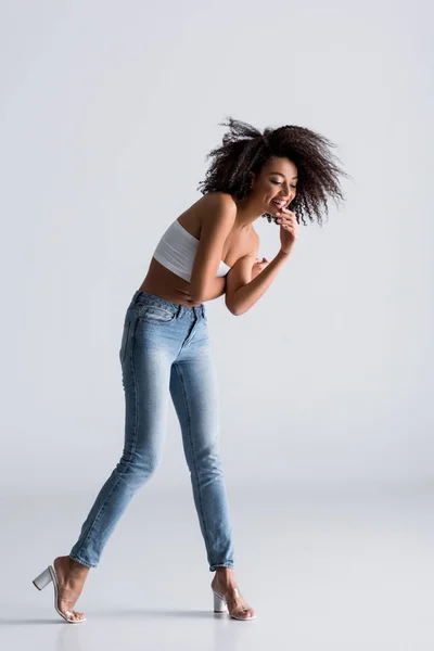 Femme afro-américaine souriante en haut blanc sur fond gris — Photo de stock