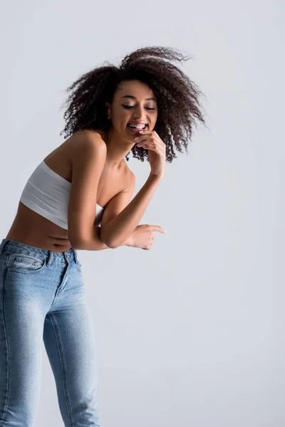 Femme afro-américaine souriante en haut blanc isolé sur gris — Photo de stock