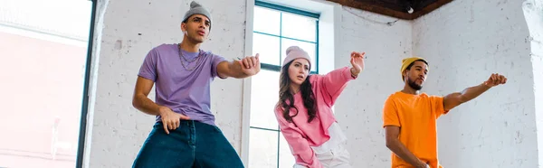 Colpo panoramico di uomini multiculturali gesticolando mentre breakdance con ragazza attraente — Foto stock