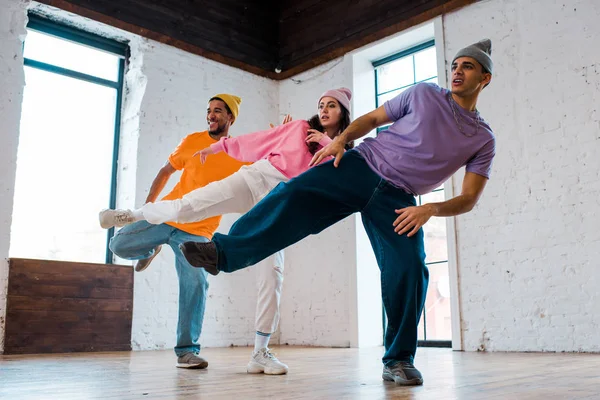 Uomini multiculturali alla moda in cappelli breakdance con bella donna — Foto stock
