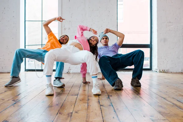 Homens multiculturais elegantes breakdancing com atraente jovem mulher — Fotografia de Stock