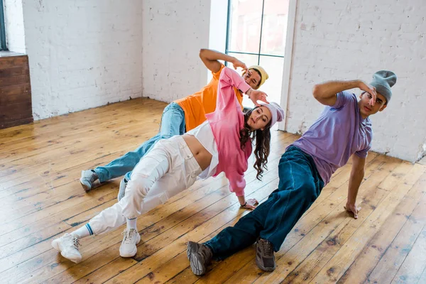 Stylish multicultural men breakdancing with young pretty woman — Stock Photo