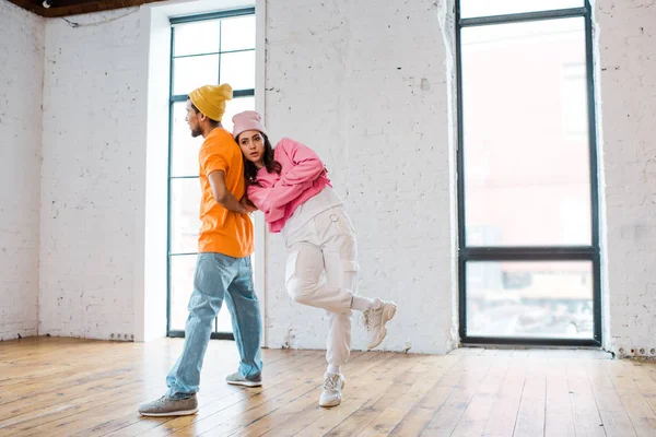 Attractive dancer posing while standing with crossed arms near african american man — Stock Photo