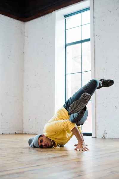Stylish man in hat breakdancing in dance studio — Stock Photo