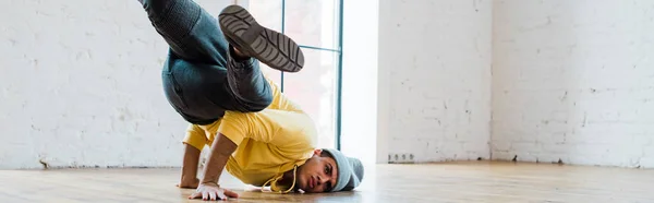 Panoramic shot of stylish man in hat breakdancing in dance studio — Stock Photo