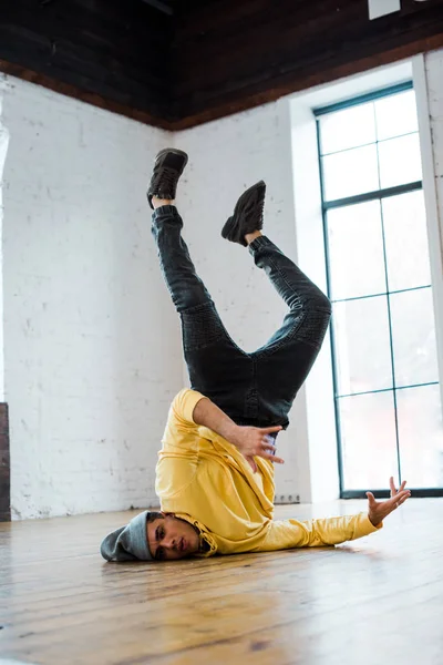 Hombre guapo en sombrero breakdancing en piso en estudio de baile - foto de stock