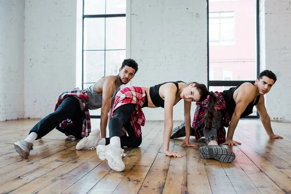 Hombres multiculturales y joven atractiva mujer bailando jazz funk - foto de stock