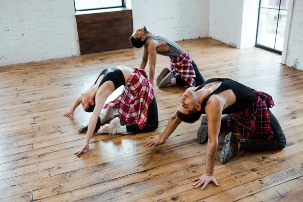 Woman and multicultural men doing wheel pose while dancing jazz funk — Stock Photo