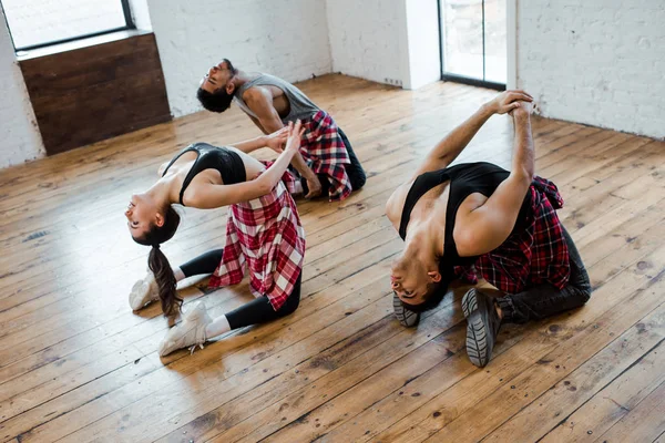 Mulher jovem e homens multiculturais dançando no estúdio de dança — Fotografia de Stock