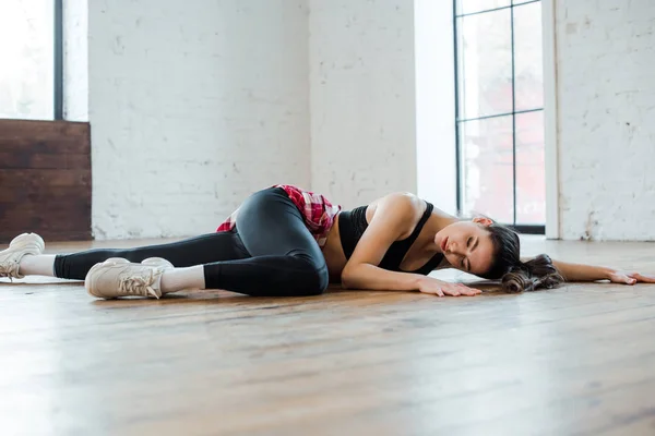 Attraktives Mädchen liegt auf dem Boden, während es Jazz-Funk im Tanzstudio tanzt — Stockfoto