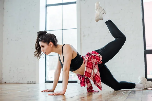 Side view of flexible woman posing while standing on knee and dancing jazz funk — Stock Photo