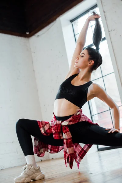 Flexible Frau posiert, während sie Haare berührt und Jazz-Funk tanzt — Stockfoto