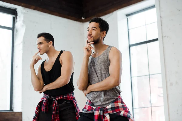 Pensativos hombres multiculturales tocando caras en estudio de danza — Stock Photo