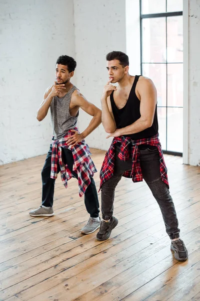 Nachdenkliche multikulturelle Tänzer berühren Gesichter, während sie im Tanzstudio posieren — Stockfoto