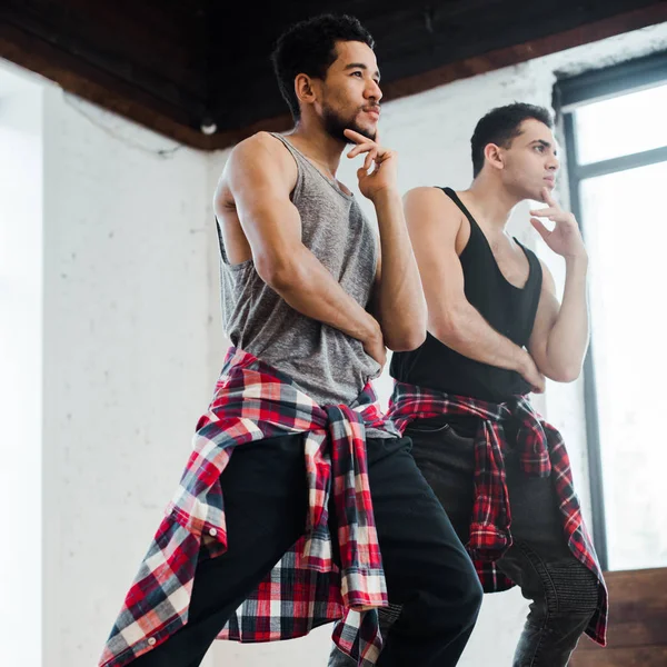 Focus selettivo di ballerini multiculturali che toccano volti mentre posano in studio di danza — Foto stock