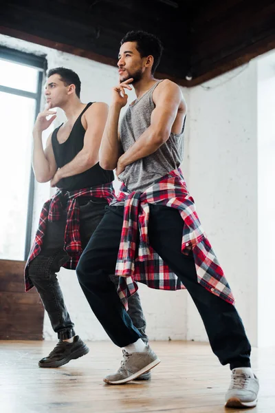 Danseurs multiculturels touchant des visages et posant dans un studio de danse — Photo de stock
