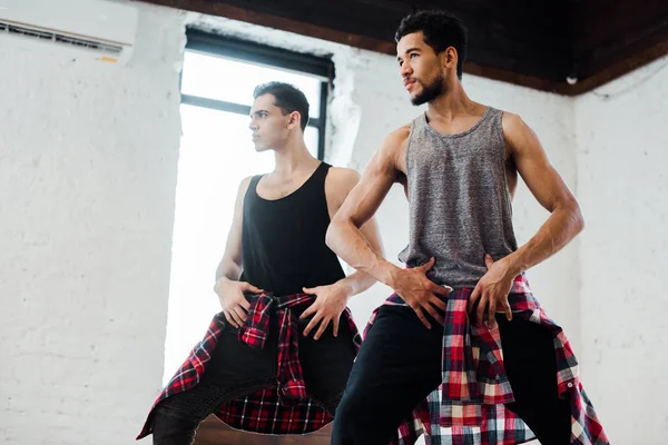 Bailarines multiculturales posando mientras bailan jazz funk en estudio de baile - foto de stock