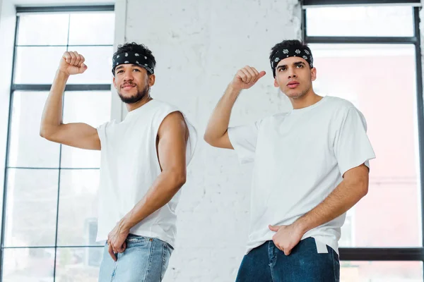 Красивые мультикультурные танцоры в повязках на голове, позирующие во время танца хип-хопа — стоковое фото