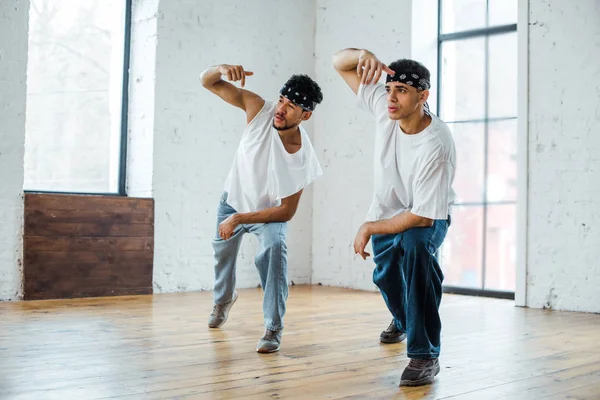 Jeunes danseurs multiculturels dans des bandeaux posant tout en dansant hip-hop — Photo de stock